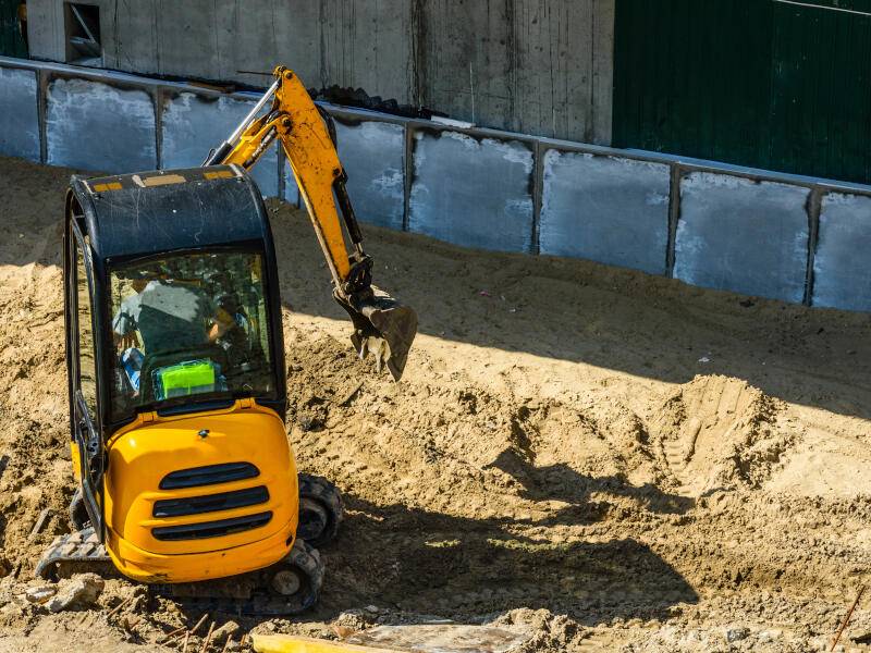 Yellow mini excavator working at the construction site